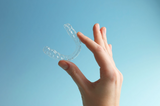hand holding a retainer after learning the benefits of wearing them