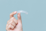 hand holding a clean retainer after learning how to clean retainers at home