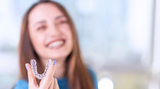 Smiling woman holding her nighttime aligners
