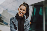 A woman wearing a jacket and scarf, looking at the camera with a beautiful smile, possibly the result of nighttime aligners.