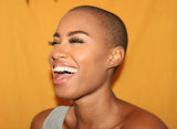 A woman with very short hair and a beaming, beautiful smile, highlighting the benefits of dental retainers.