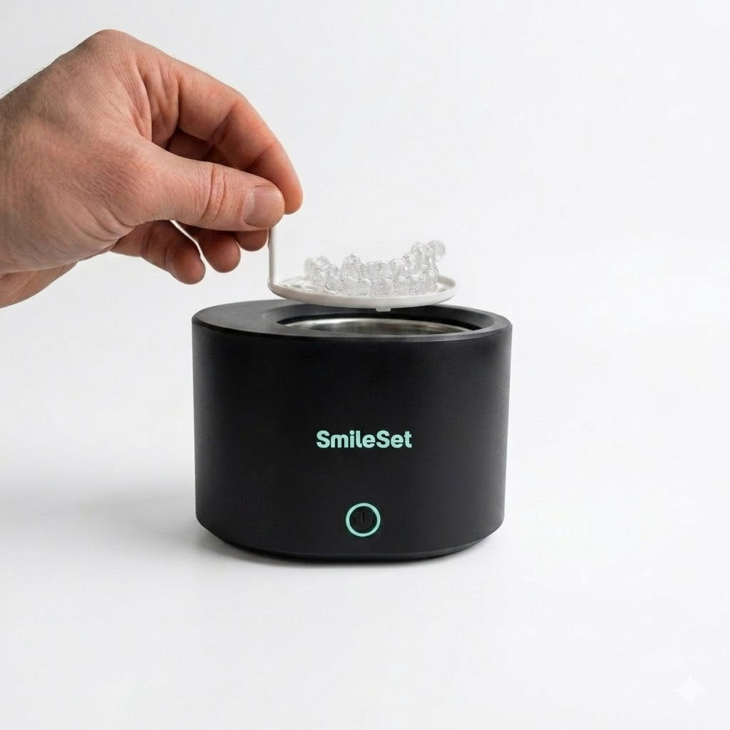 Hand placing clear retainers into the black SmileSet rechargeable ultrasonic cleaner