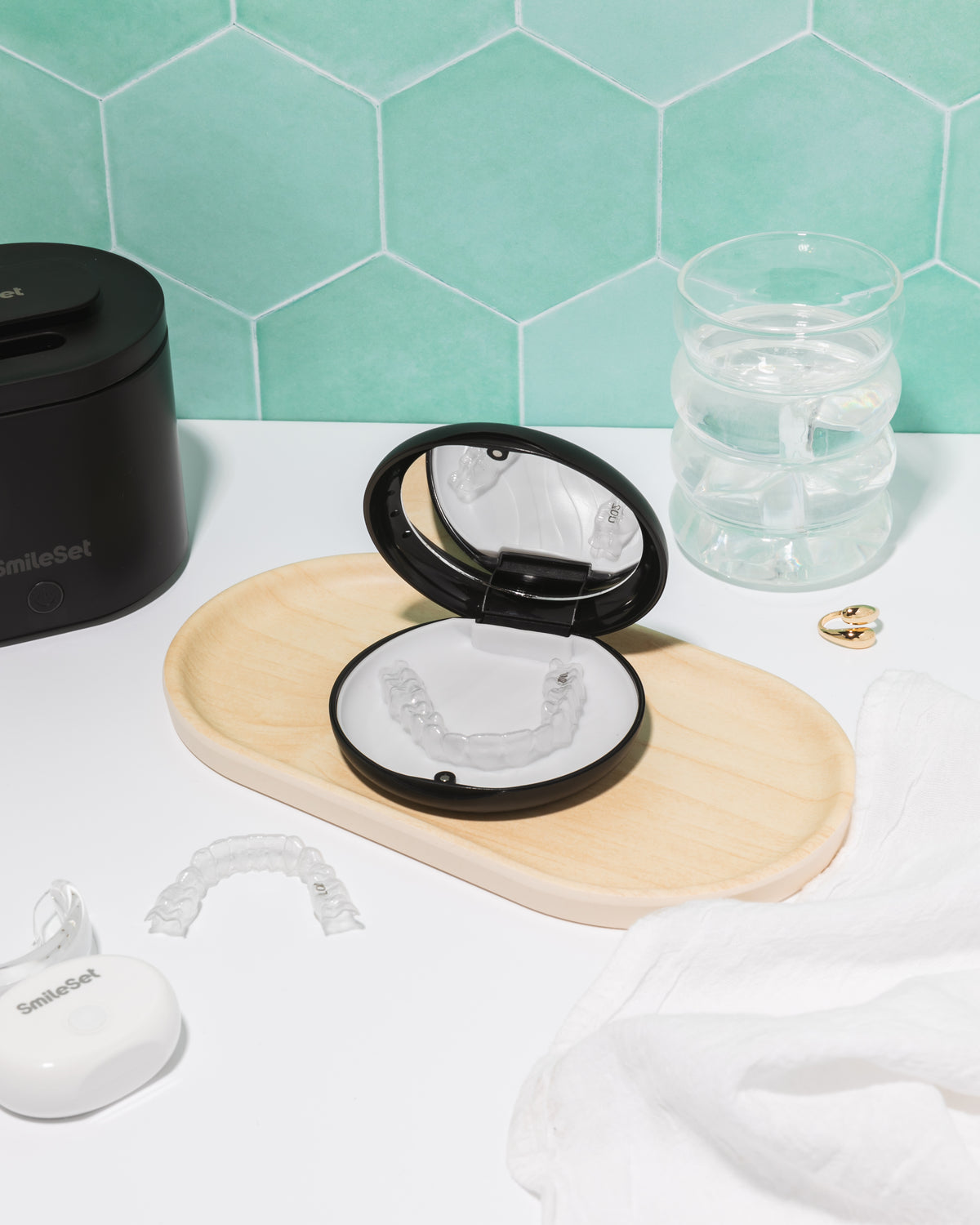 SmileSet retainer case with mirror on a bathroom counter next to clear retainers