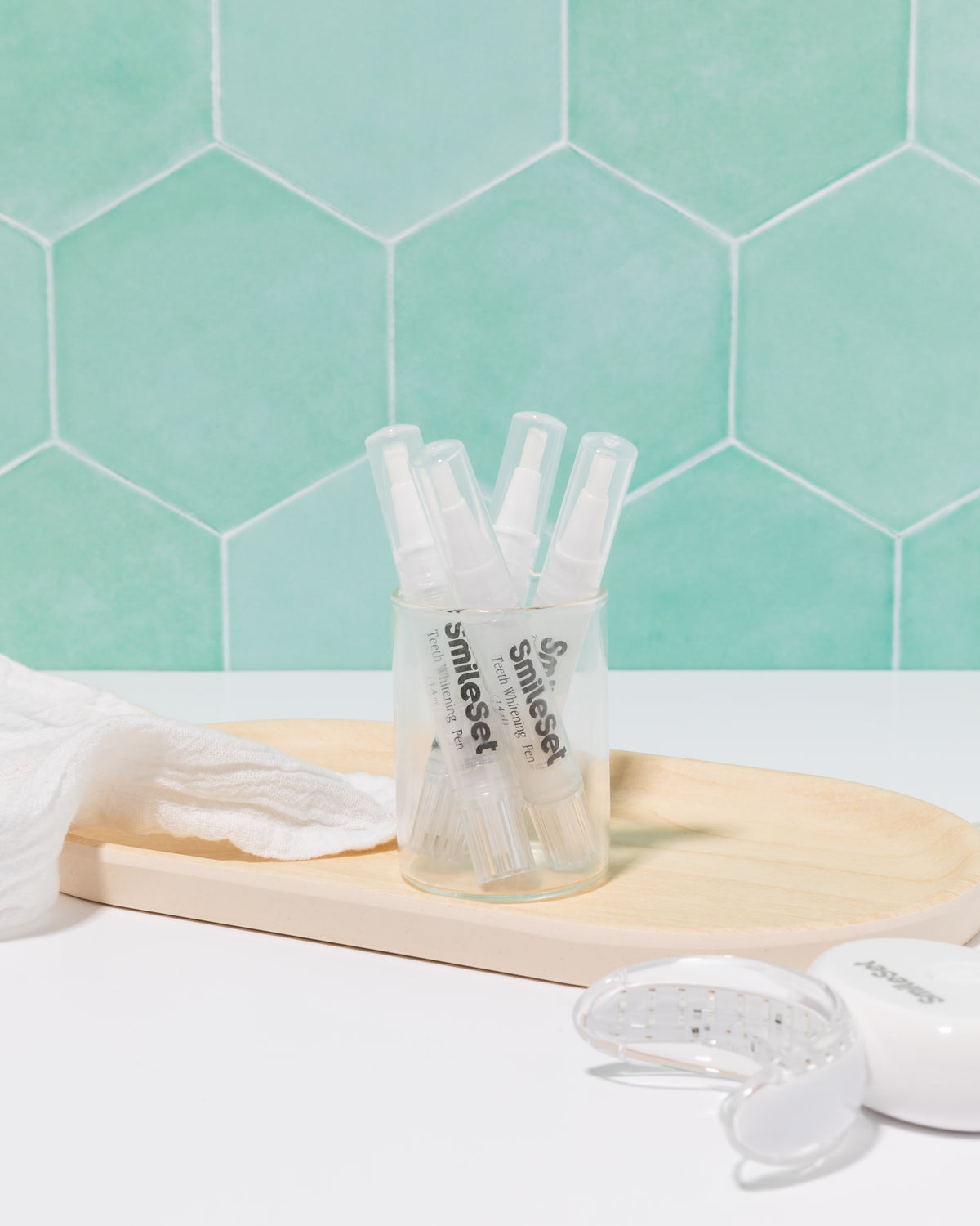 SmileSet whitening gel pens in a glass on a bathroom counter