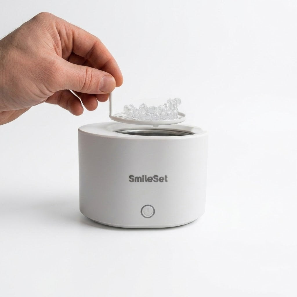 Hand placing clear retainers into the white SmileSet rechargeable ultrasonic cleaner