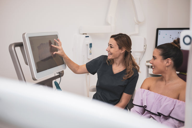 Woman in a medical setting reviewing images on a computer screen with another woman.