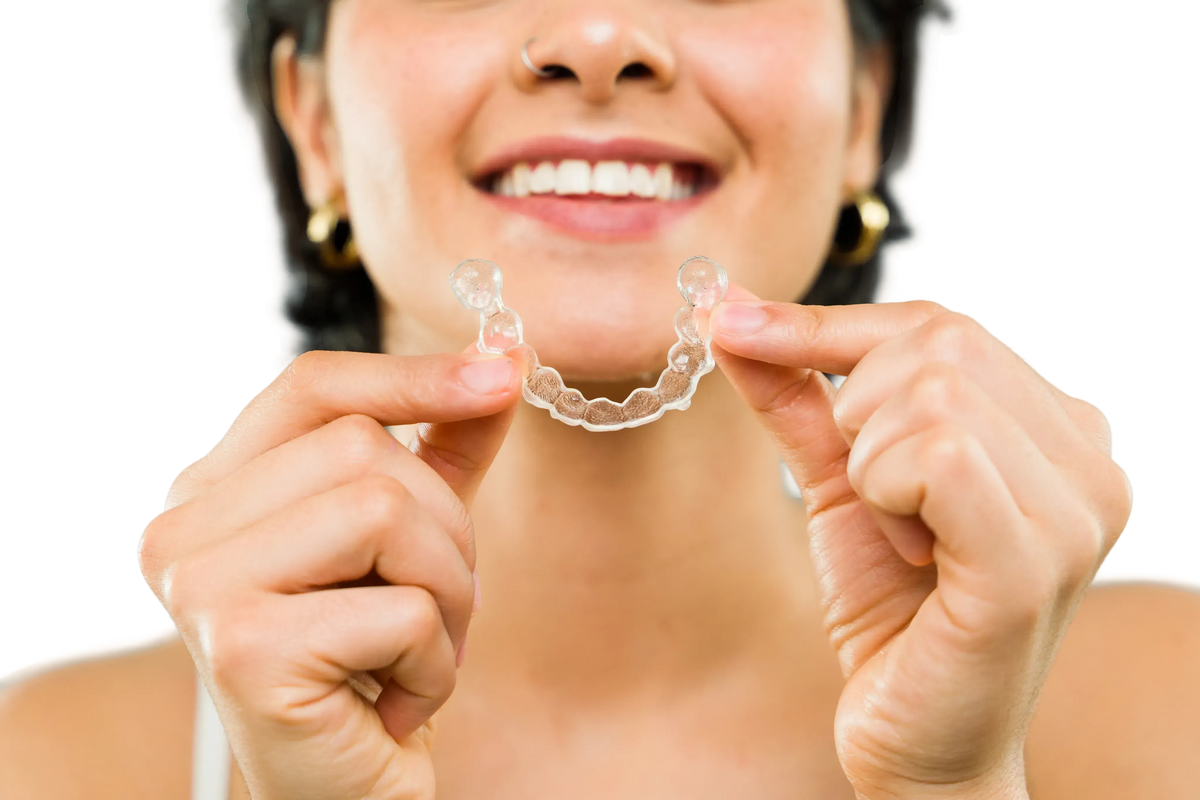 Woman holding a clear dental aligner against a white background
