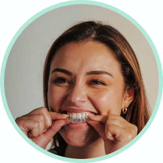 Woman smiling as she puts in a clear aligner