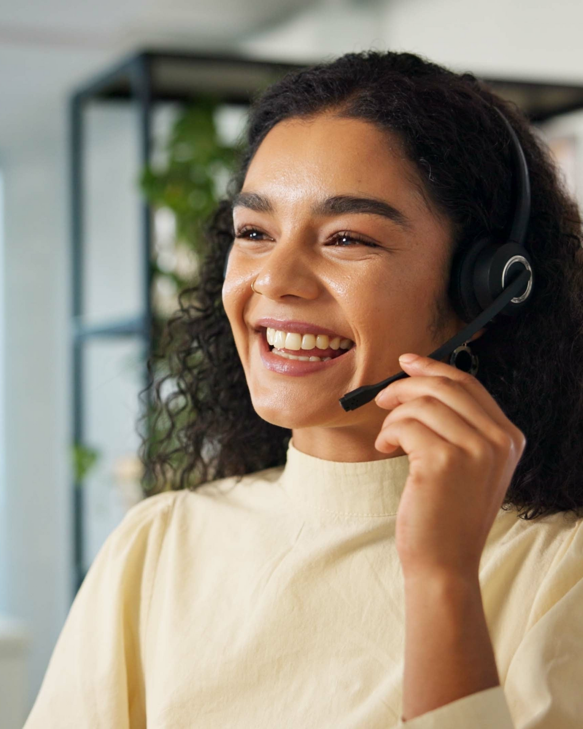Woman wearing a headset and smiling, with a blurred indoor background